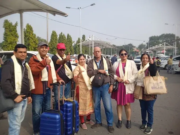 A group of travellers with white welcome scarves and luggage at the airport
