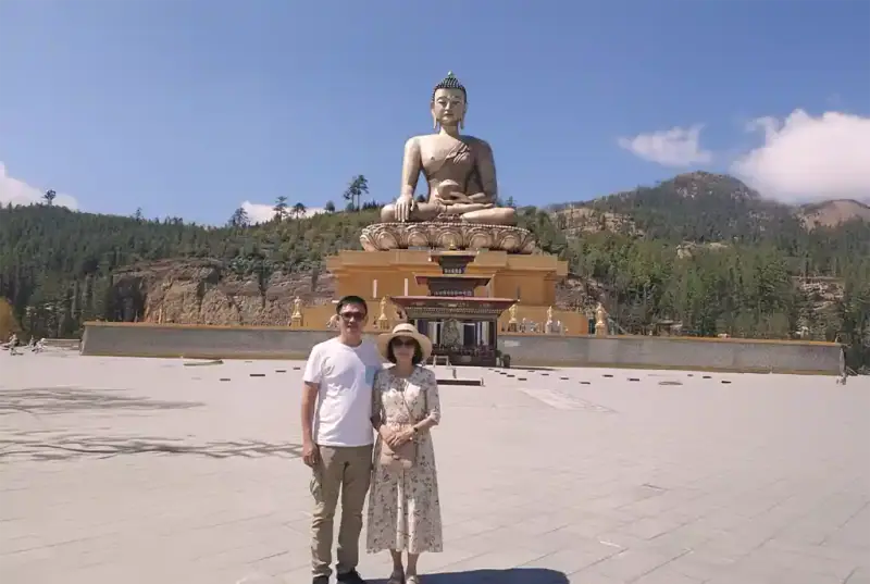 A couple standing before the Buddha Dordenma