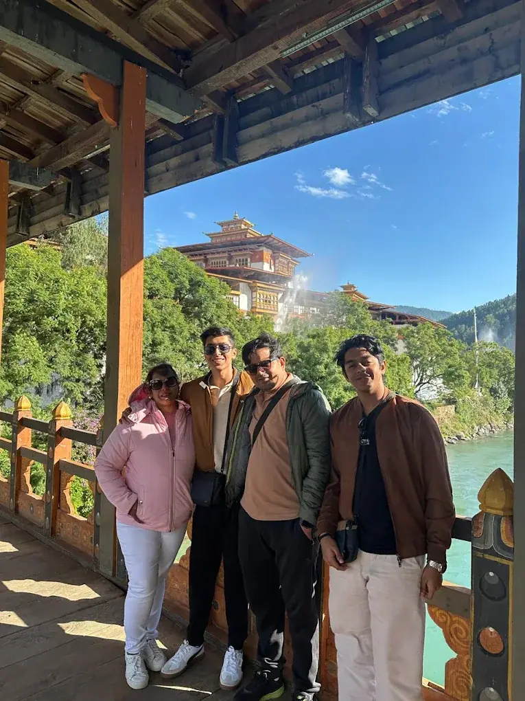 Four friends on a covered bridge with a dzong behind them