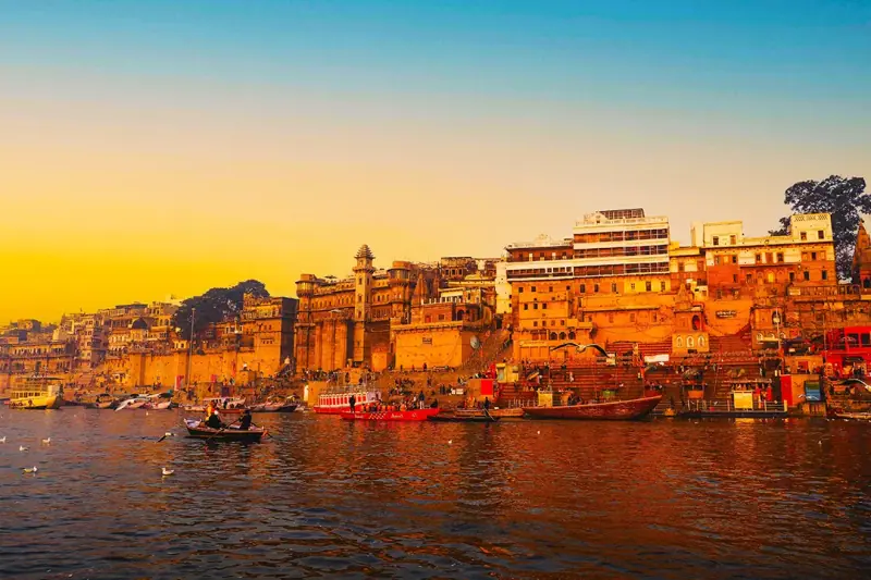 The ghats of Varanasi glowing at sunset across the Ganga