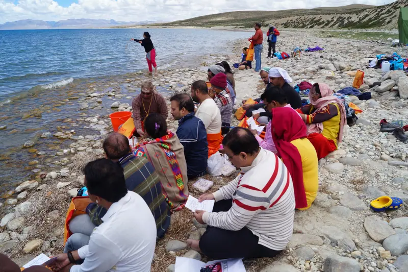 Pilgrims performing a puja on the stony shore of the lake