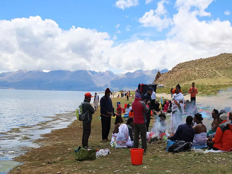 Pilgrims gathered on the shore of Lake Mansarovar under a bright sky