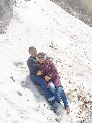 A couple sitting in the snow on a mountain slope